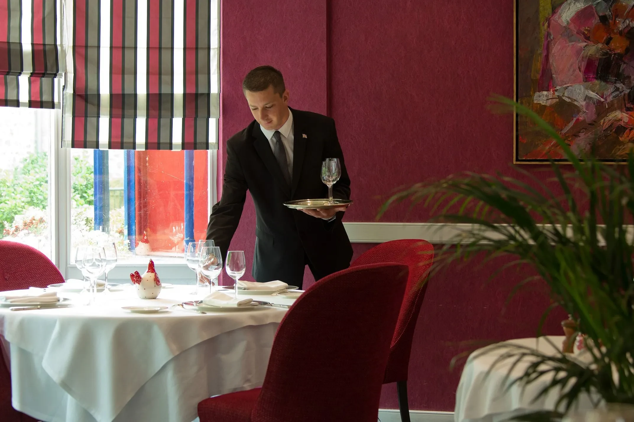 Serveur préparant une table élégante dans un Restaurant Gastronomique à Sarthe.