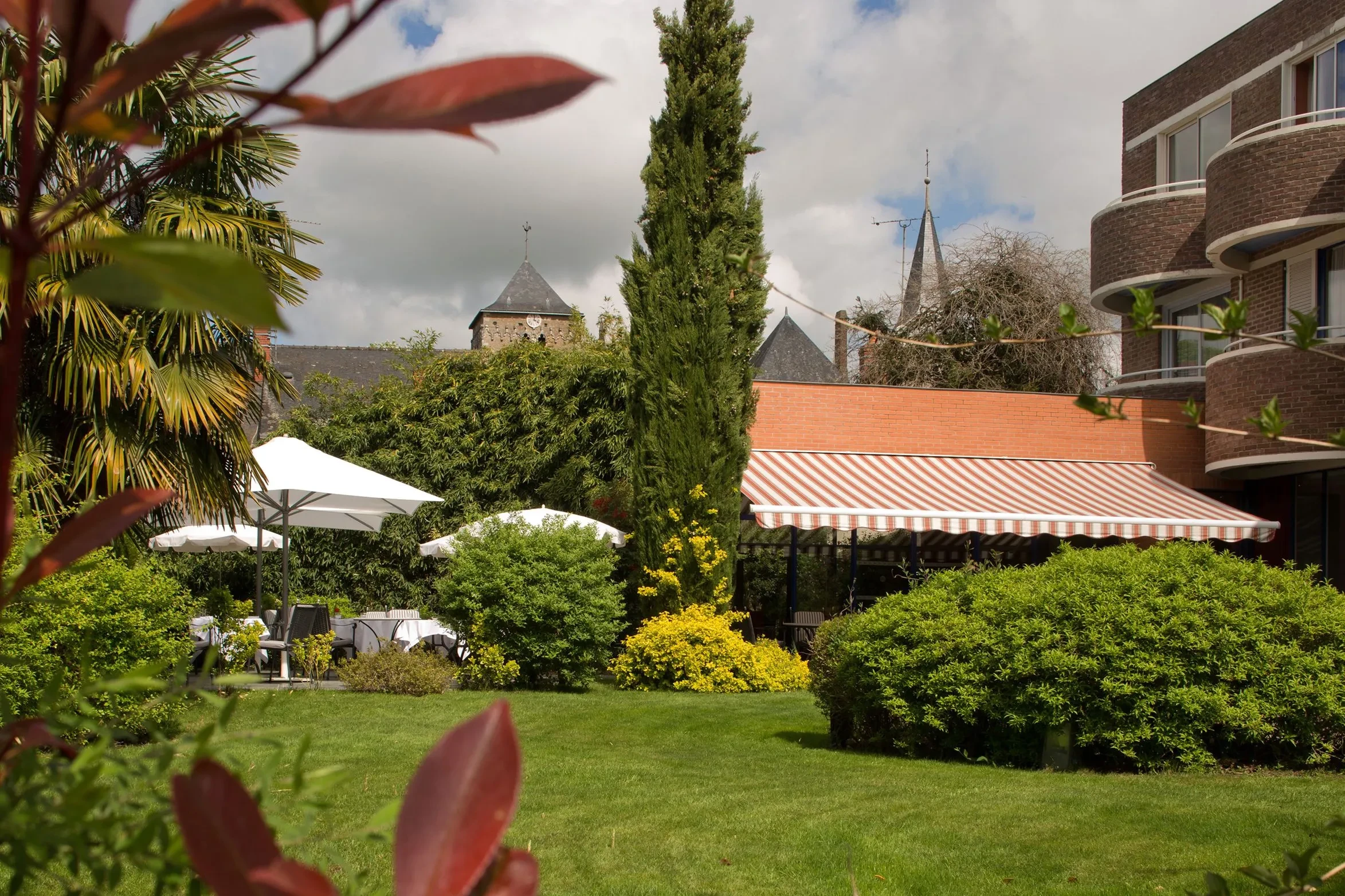 Jardin avec parasols et bâtiment en brique.