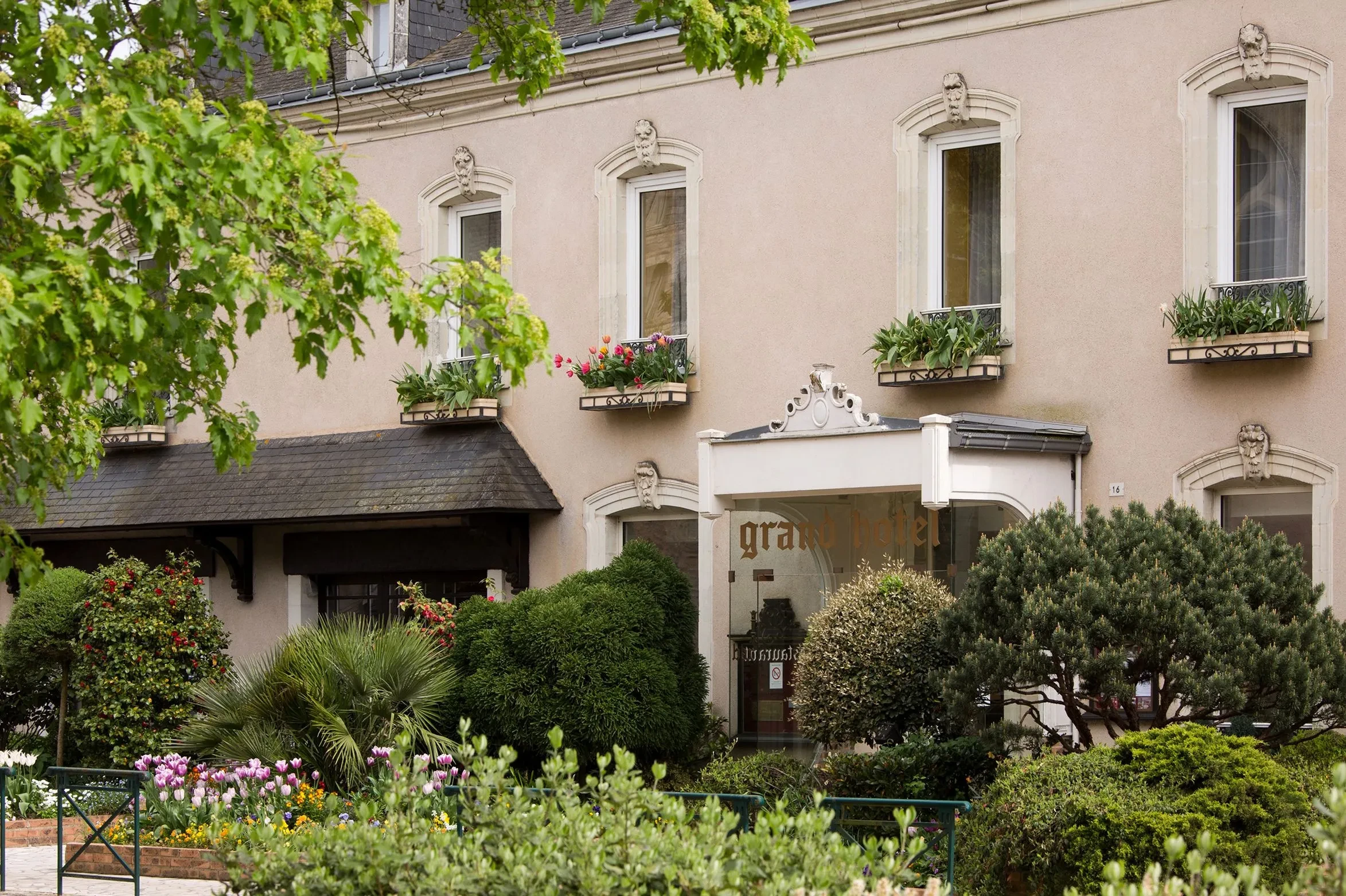 Façade d'Hôtel Solesmes avec jardins et fenêtres fleuries.