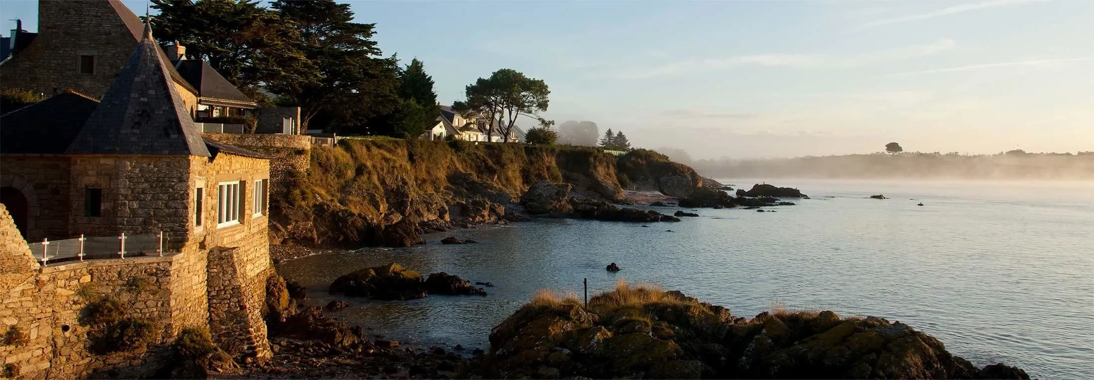 Maison sur falaise, bord de mer ensoleillé.